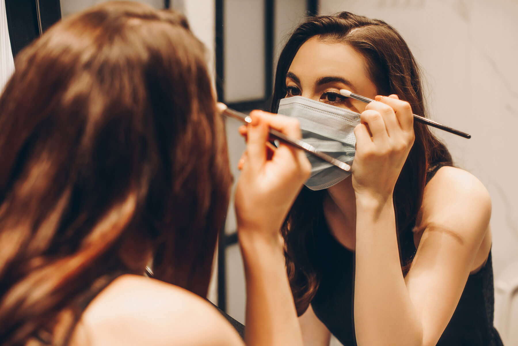 Impact-of-Covid-on-beauty---woman-applying-makeup-with-mask