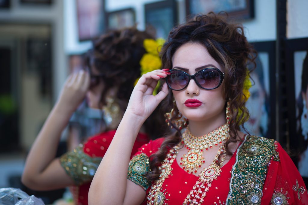 Glamorous Indian woman dressed in red looking over sunglasses