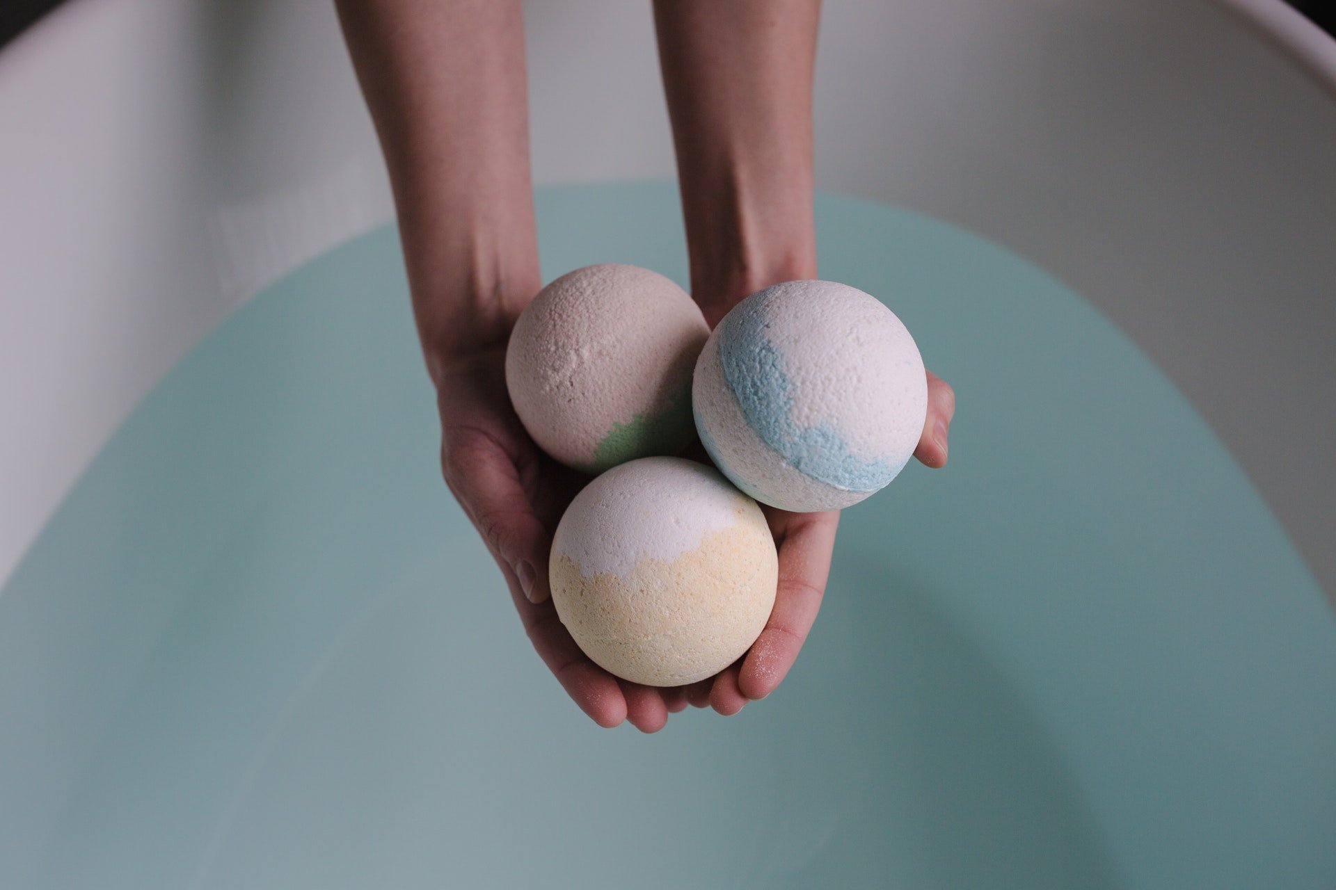 3 Lush bath bombs being held over a bath